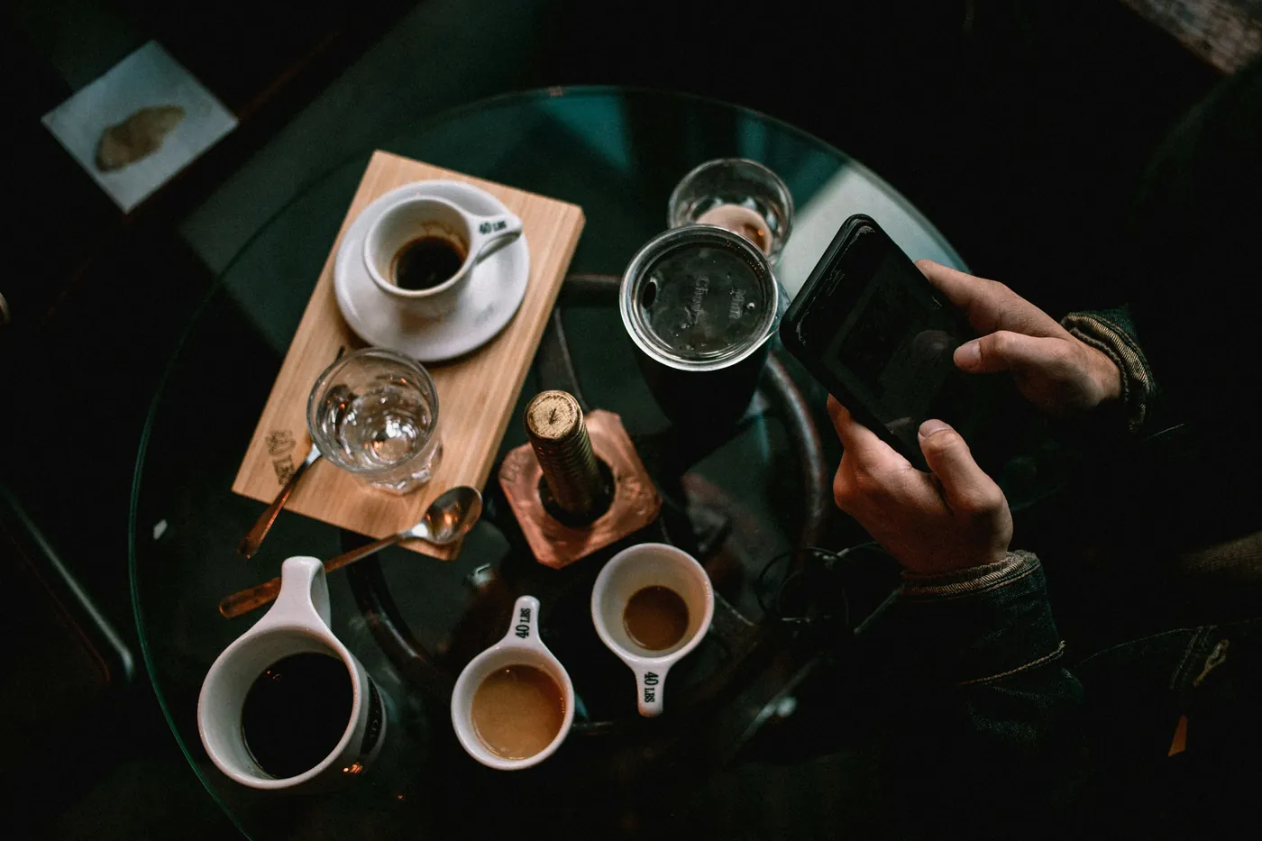 A guest at a café table with a coffee, holding a phone